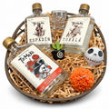 Arcón redondo con tres botellas de 250 ml de Tío Meke —Espadín, Tobalá y Frutas de Altar y Cempasúchil—, caballito calavera, vela de cempasúchil y figuras decorativas